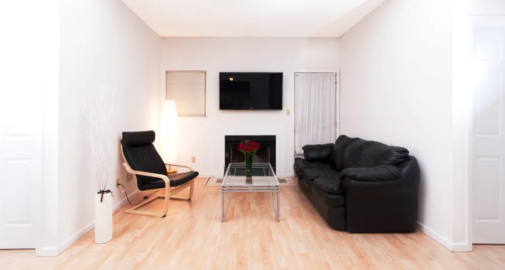 Living room with wood floor and wood burning fireplace at Campus Oaks Apartments