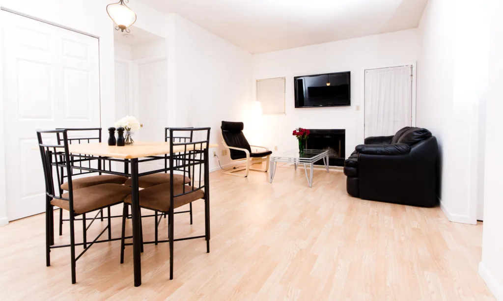 Furnished living room with leather sofa and 65 inch flat screen TV at Campus Oaks Apartments